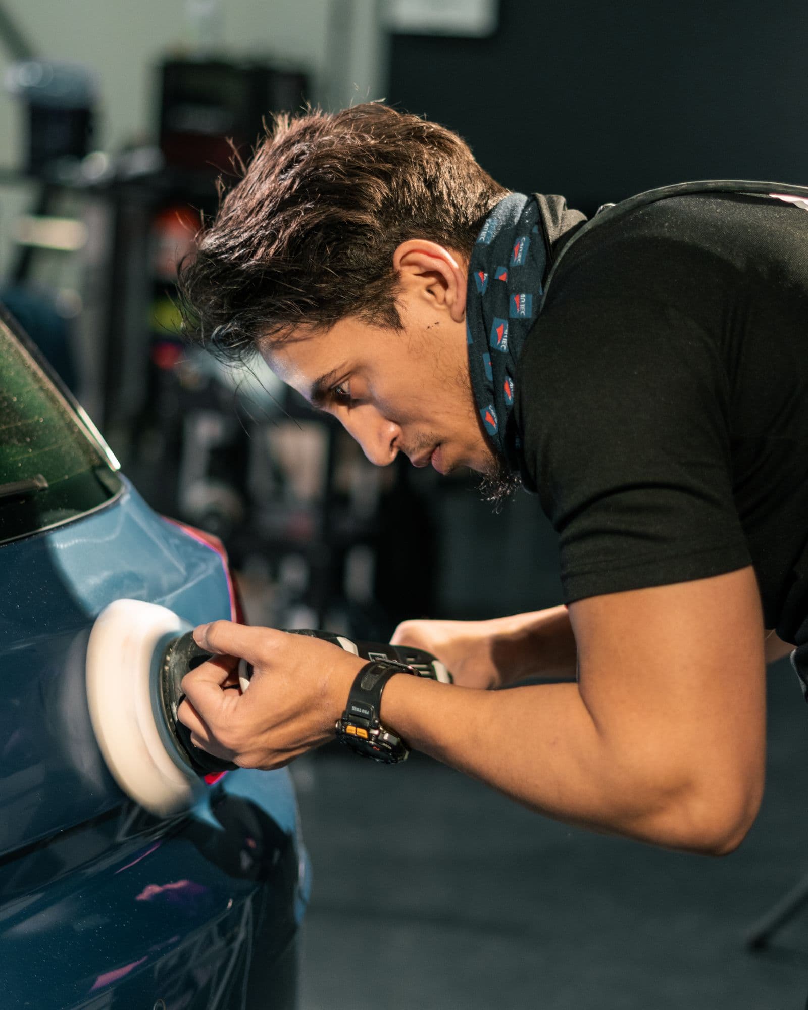 A detailer using a rotary buffer on a car panel