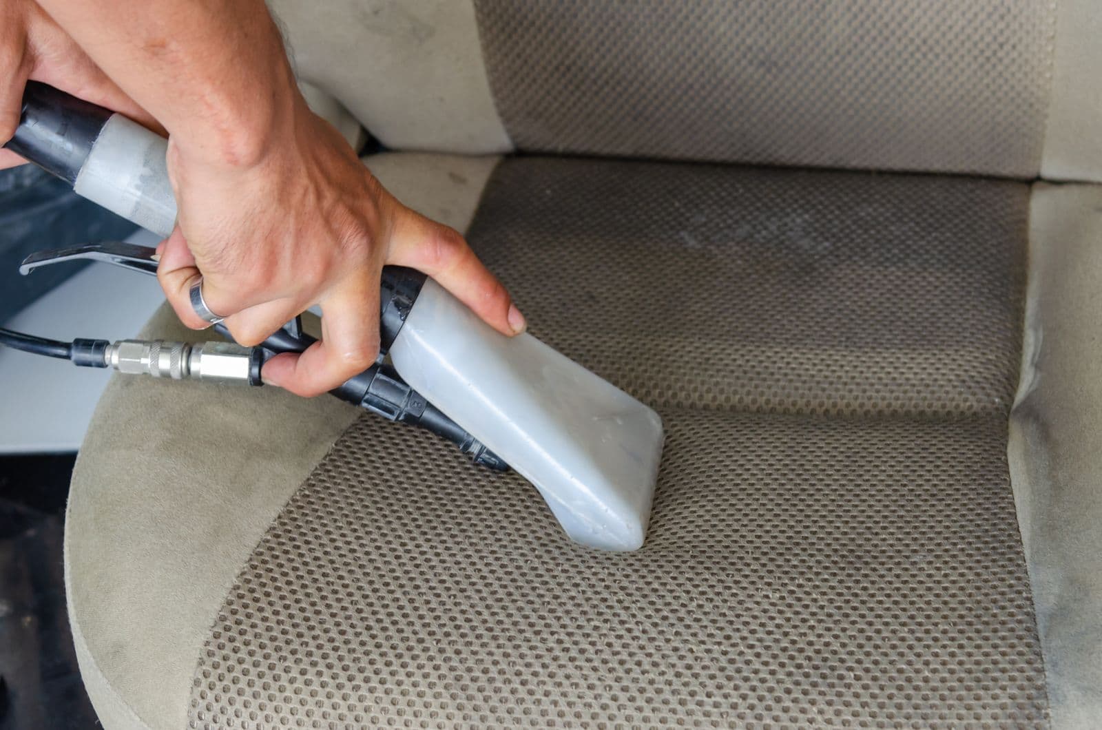 Steam extraction tool deep-cleaning a car seat