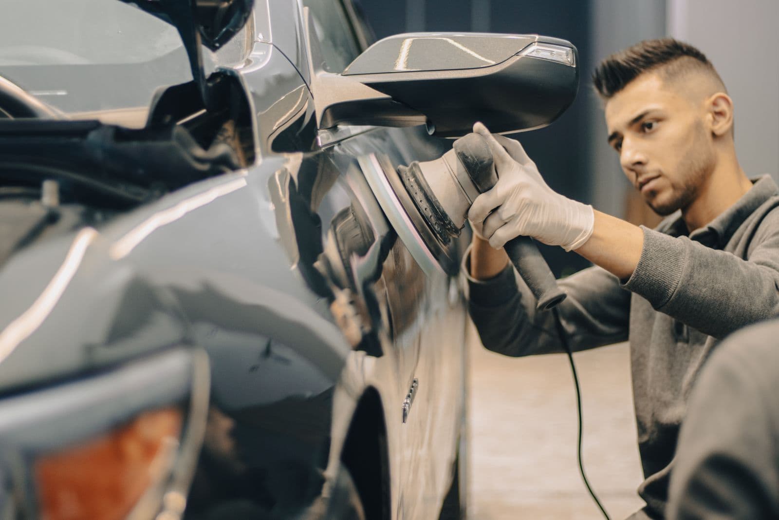 A detailer polishing a wing mirror wearing nitrile gloves